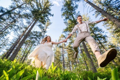 Menyasszony és vőlegény vidáman futnak Ausztriában az erdőben