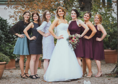 Menyasszony áll a csoportképen a koszorúslányokkal mosolyogva