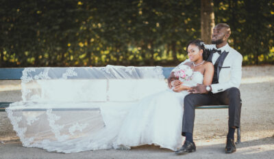 A friss házasok ülnek a padon, kiengedve a ruha fátylát