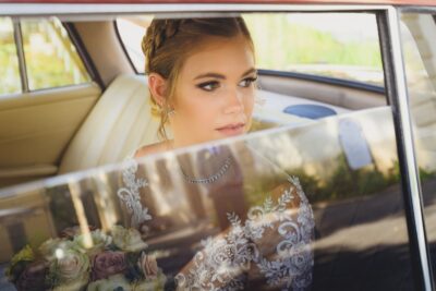 Menyasszony nézi a vőlegényét egy autóban ülve