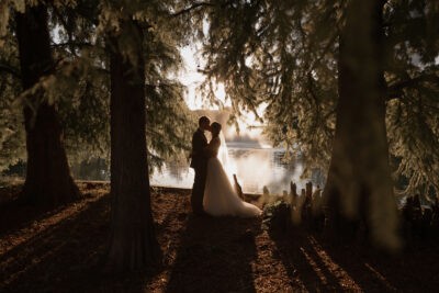 Csókolózó házaspár a tó partján és fák között